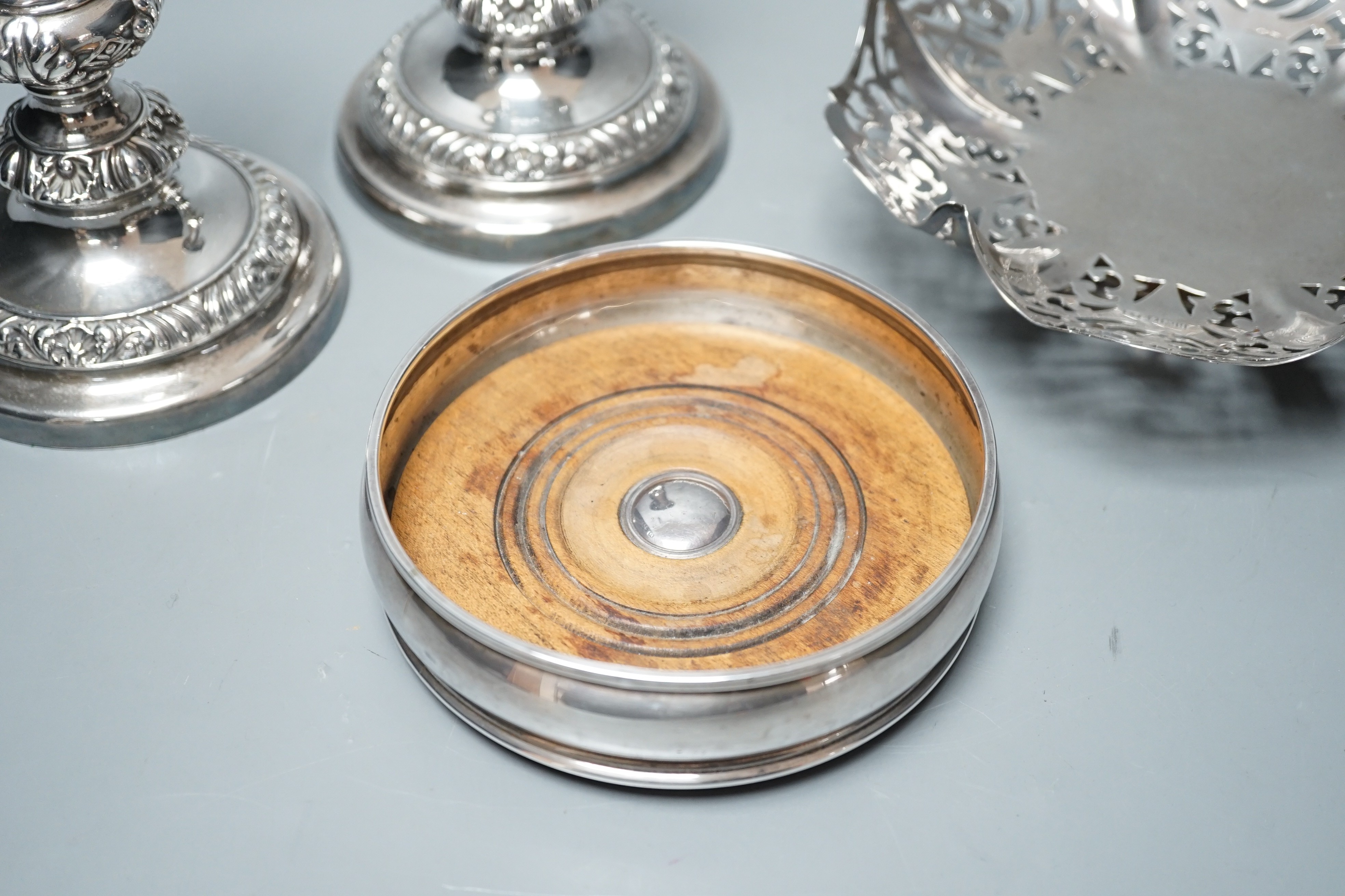 A modern silver mounted wine coaster, London, 1996, diameter 12.4cm, an earlier pierced silver bonbon dish and a pair of plated candlesticks.